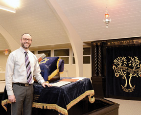 BIAV Rabbi Daniel Rockoff stands at the bimah in the Orthodox congregation’s newly renovated sanctuary. The ark, bimah and eternal flame were all refurbished and relocated on the eastern wall. (Photo by Cathy Donovan)