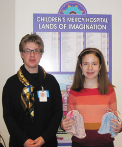 CAPS FOR CANCER — Laura Martasin, (right) the daughter of Debra and Jeffrey Martasin, became a Bat Mitzvah Dec. 1 at The Temple, Congregation B’nai Jehudah and recently completed her mitzvah project. A seventh-grade student at Indian Hills Middle School, she knitted chemo caps for cancer patients undergoing treatment at Children’s Mercy Hospitals and Clinics. She began knitting about a year ago and this was a way to put her new talents to good use. Recently Laura delivered the caps to the hospital’s Volunteer Services Department in downtown Kansas City. Shown here with Laura and her knitted caps is Camille Grewing, hospitality assistant at Children’s Mercy Hospitals and Clinics.