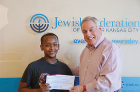Photo by Jonathan Edelman: Executive Vice President and CEO of the Jewish Federation of Greater Kansas City Todd Stettner presented the Durwood Family Foundation $8,000 scholarship grant to Hyman Brand Hebrew Academy seventh-grader Yonaton Mehari at the school’s May 21 board meeting. Stettner explained it was the desire of the Foundation’s Ray Beagle to help a well-rounded, bright and deserving student obtain a private school education, just as he had been helped in his youth by a generous donor. Yonaton is the son of Girmay Mehari and Tsenganesh Hailu. The family said, “There are no words to express our gratitude to the Federation, the Foundation, HBHA and to Miriam and Dan Scharf who played an integral role in contacting the Durwood Family Foundation.”