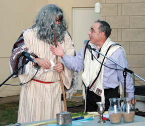 We got a big kick out of this photo Congregation Beth Torah sent in. On Erev Sukkot Moses (played by Aaron Nielsenshultz) dropped in to help annouce the congregation’s Torah writing project. Here he discusses the details of the this once-in-a-lifetime experience with Rabbi Mark Levin. You can learn more about the Torah writing project on this site.